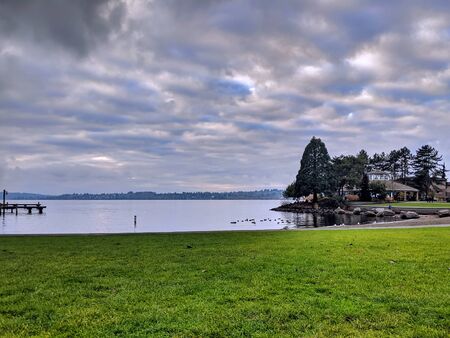View of Lake Washington from the downtown marina beach in Kirkland, WA, clouds hanging over the waterの写真素材