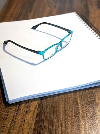 Teal glasses thoughtfully placed on top of a white spiral drawing notebook