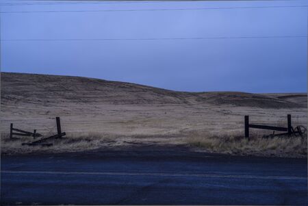 Night view of a wide, empty yellow farm land in the Pacific Northwest on an overcast day, separated...
