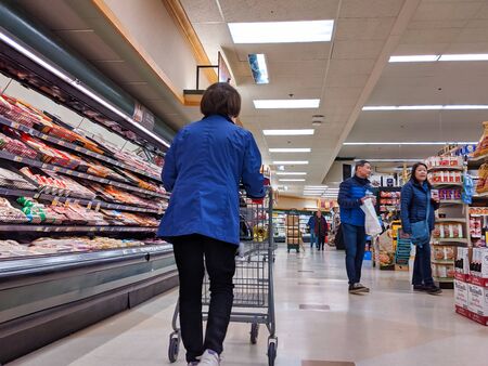 Bellevue, WA / USA - circa January 2020: People shopping for groceries inside a QFC grocery store near the meat department.のeditorial素材