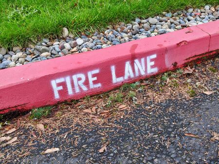 Downward angle of a bright red fire lane sign on a curb in a suburban neighborhoodの写真素材