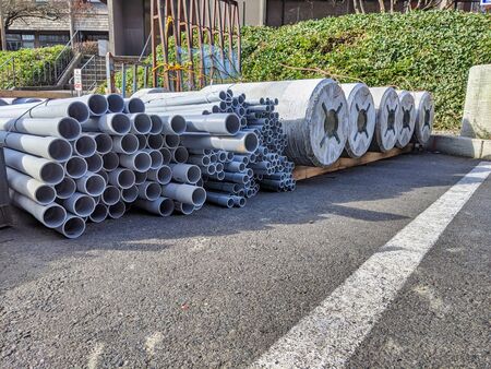 Street view of construction equipment outside of a work site, including steel pipes of various sizes