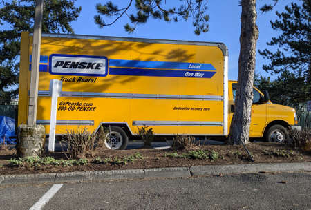 Kirkland, WA / USA - circa March 2020: Street view of a bright yellow Penske rental truck in a...