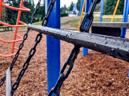 Selective focus on a chain climbing net on a bright, colorful playground on a rainy dayの写真素材