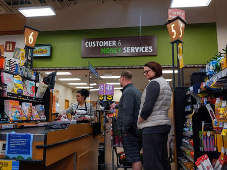 Kirkland, WA / USA - circa April 2020: Cashier behind a plexiglass wall at a checkout counter inside a Fred Meyer grocery store during the coronavirus outbreakのeditorial素材