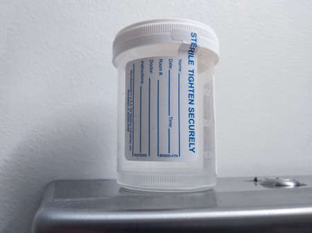 Kirkland, WA / USA - circa April 2020: Empty urine sample cup inside a hospital restroom.のeditorial素材