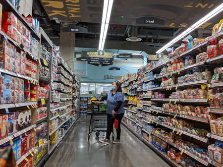 Kirkland, WA / USA - circa April 2020: Woman wearing a face mask and shopping in the baking aisle...