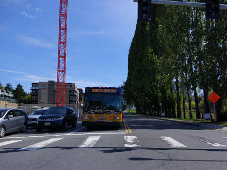 Kirkland, WA / USA - circa May 2020: Street view of a King County Metro bus at a red light, stating...