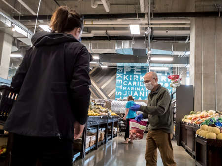 Seattle, WA / USA - circa May 2020: Elderly man wearing a face mask while grocery shopping inside a...