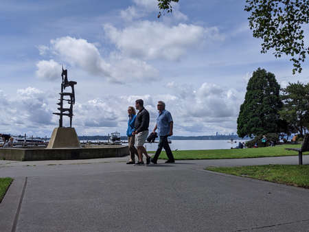 Kirkland, WA / USA - circa July 2020: People walking by the beach at the Kirkland Marina at Lake...