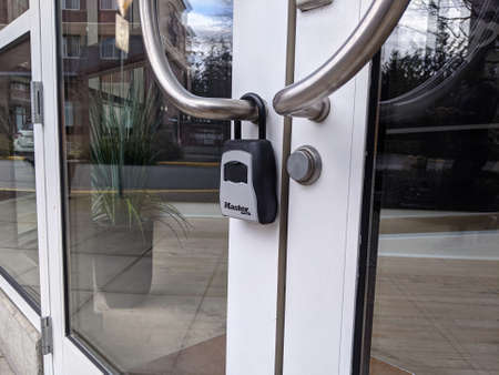 Redmond, WA USA - circa March 2021: Close up view of a Master Lock padlock on large, glass doors.のeditorial素材