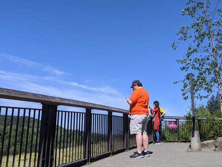 Snoqualmie, WA / USA - circa May 2020: Pedestrians viewing the majestic Snoqualmie Falls from one of the viewpoints on a sunny day.のeditorial素材