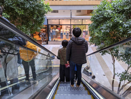 Bellevue, WA USA - circa March 2021:People wearing face masks descending on an escalator at the Bellevue Mallのeditorial素材