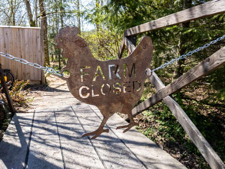 View of a metal Farm Closed sign blocking the entrance on a wooden bridgeの写真素材