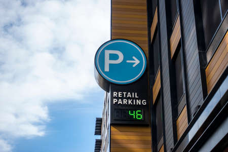 Low angle view of a baby blue digital parking sign for a parking garage in a shopping district...