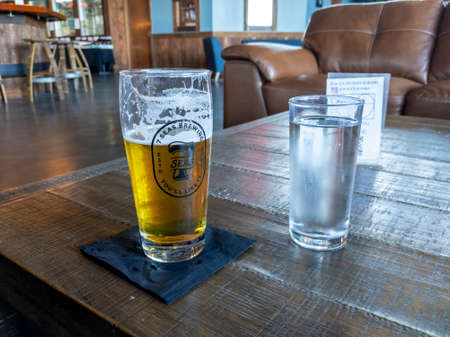Tacoma, WA USA - circa August 2021: View of a foamy pilsner beer on a rustic table at 7 Seas Brewery.のeditorial素材