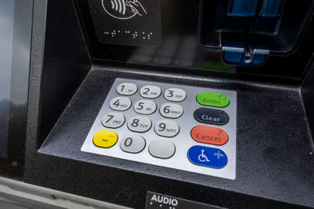 Angled view of an ATM number pin pad and check deposit slot at an outdoor machine outside of a bank.の写真素材