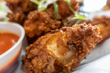 Close up of deliciously golden and fried chicken wings in a basket, next to cups of ranch and hot sauceの写真素材