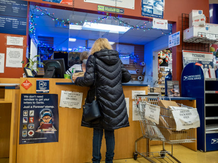 Kirkland, WA USA - circa December 2021: Angled view of a person shipping a package at a USPS during...