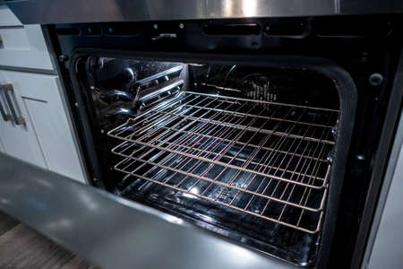 Angled view of the inside of a clean, black oven, the door slightly open