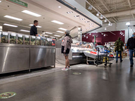 Lynnwood, WA USA - circa March 2022: View of a woman shopping at the seafood counter inside a Town...