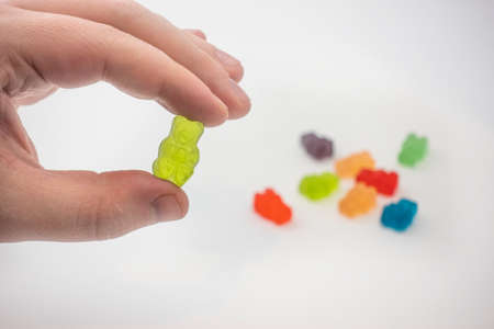 View of a male hand holding a colorful CBD infused medicinal candy gummy used for healing