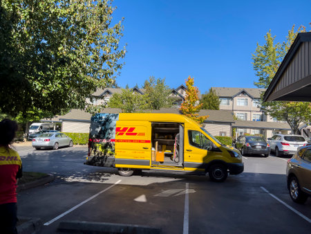 Seattle, WA USA - circa October 2022: Wide angle view of a DHL delivery van making a stop in a large apartment complex on a bright, sunny day.のeditorial素材