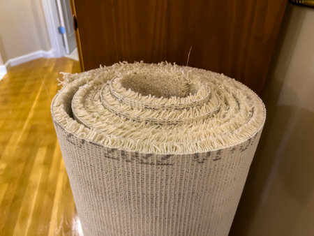Close up view of a rolled up, old carpet leaning against a wooden bookcase