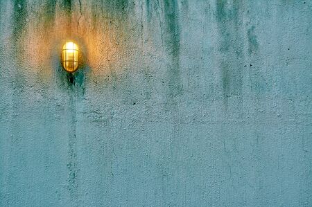 Blue grunge concrete wall with lamp and green moss for background or texture. Negative space can be used to put words or quotationの写真素材