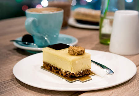 Pistachio Cheesecake in white plate with blurred hot coffee and sugar in background. A slice of cheesecake chocolate variantの写真素材