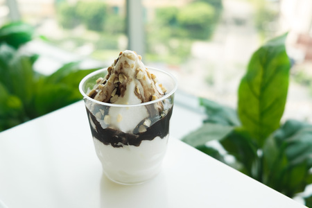 Ice Cream Sundae with Chocolate and Walnut on plastic glass on white tableの写真素材