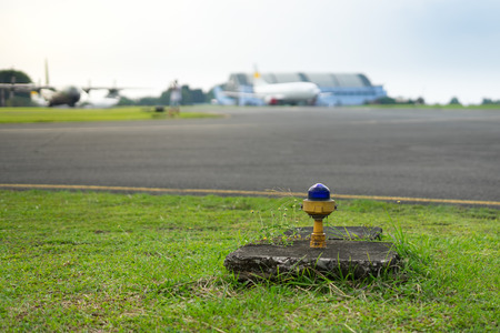 Safety Edge Blue Light Beside Airport Taxiway with Blur Airplane on Backgroundの写真素材