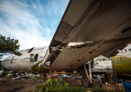 Big Old Jetliner Being Cut To Pieces For Recyling Purpose at Airplane Graveyard Under The Blue Cloudy Sky. Under Wing Part Being Dismantle of Its Componentの写真素材
