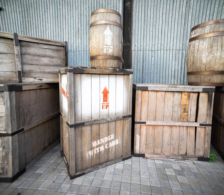Old and Damage Vintage Wooden Box and Drum In Front of Warehouse. One Box has Handle With Care Written On Itの写真素材