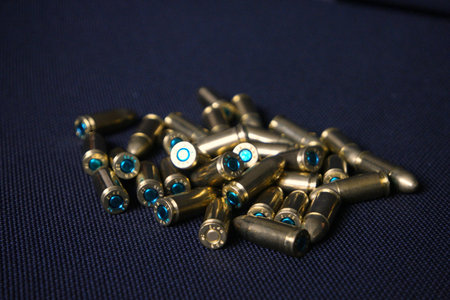 Close-up macro shot of brass rifle cartridges arranged in a black plastic tray. The image highlights...