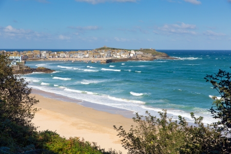 Porthminster beach with St Ives Cornwall in the background and white waves and blue sea and sky on a beautiful summer dayの写真素材