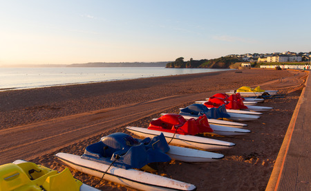 Pedalos Goodrington beach near Paignton Devon England with colourful beach huts on a summer morning の写真素材