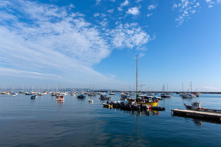 Boats by the yacht club Brixham harbour Devon England UK on a calm summer day with blue sky