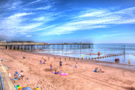 Holidaymakers on Teignmouth pier and beach Devon England UK with blue sky and clouds in colourful HDRのeditorial素材