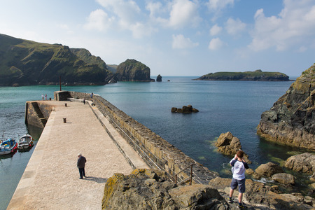 Tourists on harbour wall Mullion Cove Lizard peninsula south Cornwall UK situated on Mounts Bay near Helston within the Cornish Area of Outstanding Natural Beautyのeditorial素材