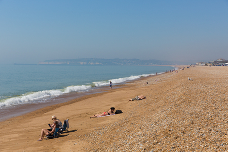 Seaford beach with people sunbathing and waves East Sussex UKのeditorial素材