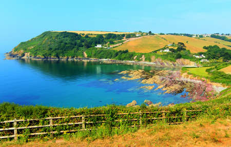 Talland Bay Cornwall UK with colourful red and purple rocks and clear seaの写真素材