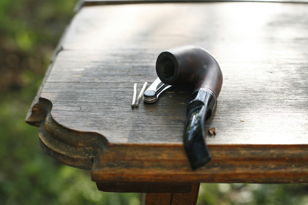 Tobacco brown pipe with accessories  in wooden  table