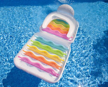 Colorful floating air mattress in swimming pool at summertime as background