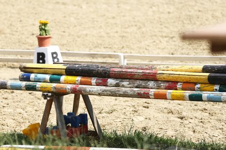 Colorful jump obstacles for equestrian sports outdoors against sandy trackの写真素材