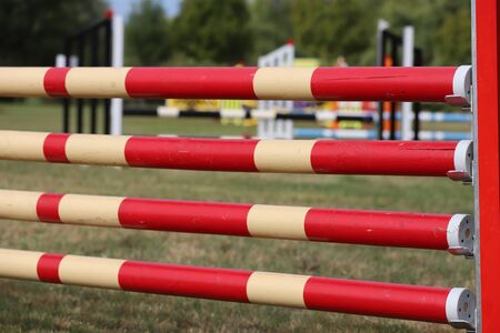 Image of show jumping poles on empty training field. Wooden barriers for jumping horses as a background. Colorful photo of equestrian obstacles. Empty field for horse jumping event competitionの写真素材