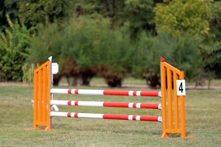 Image of show jumping poles on empty training field. Wooden barriers for jumping horses as a background. Colorful photo of equestrian obstacles. Empty field for horse jumping event competitionの写真素材