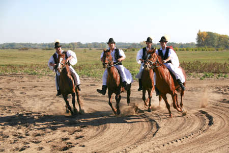 PUSZTA, HUNGARY, SEPTEMBER, 04. 2020: Hungarian herdsmen as csikos in traditional folk costume showing his trained horses in the puszta hungarian lowlands. September 04. 2020, Hungary Easternのeditorial素材