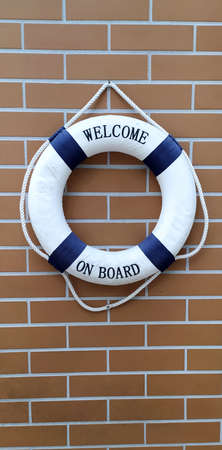 Blue and white colored lifebelt hanging on the brick wall of the sailing clubhouse