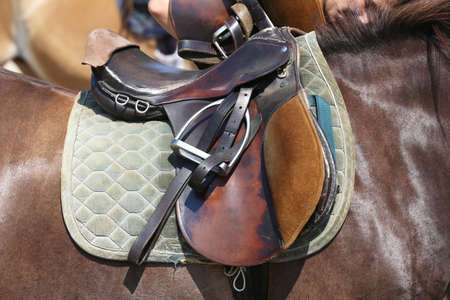 Close up of a sport horse saddle. Old quality leather saddle ready for show jumping event. Equestrian sport background outdoorsの写真素材